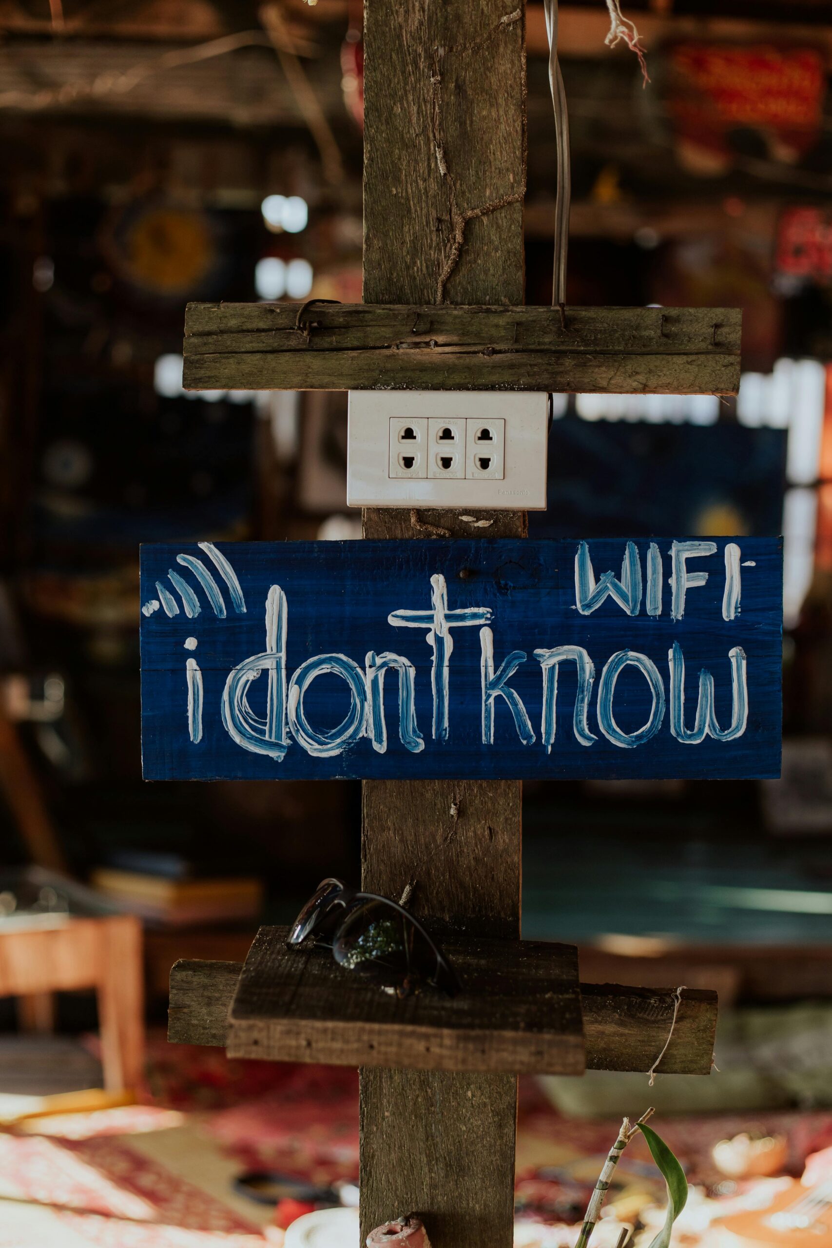 Close-up of a wooden sign humorously displaying Wi-Fi password in a rustic setting.